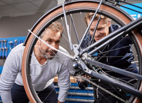 A Shimano employee and a customer looking at the bicycle wheel